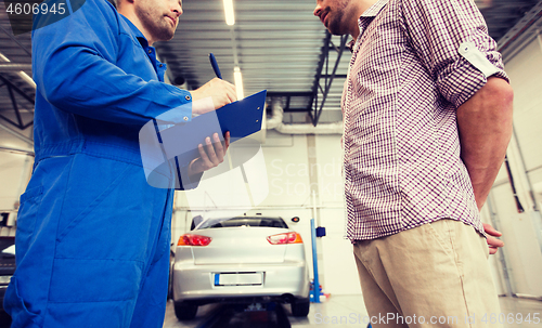 Image of auto mechanic with clipboard and man at car shop