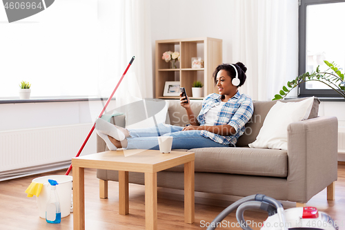 Image of woman in headphones resting after home cleaning