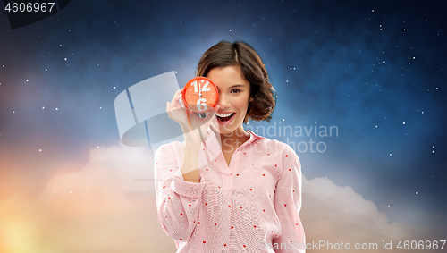 Image of happy young woman in pajama with alarm clock