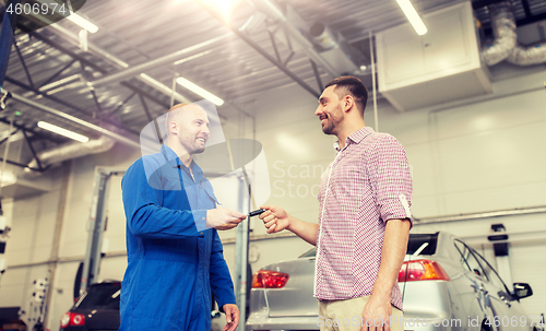 Image of auto mechanic giving key to man at car shop