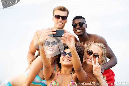 Image of happy friends taking selfie on summer beach