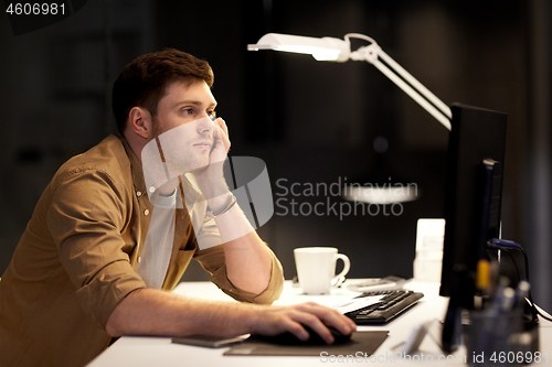 Image of tired or bored man working late at night office