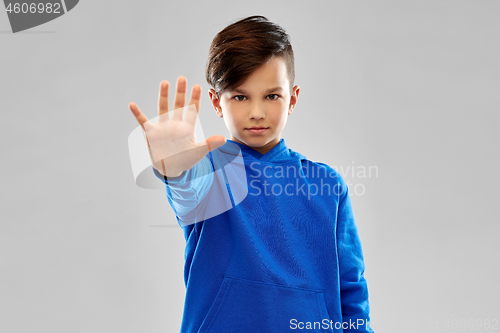 Image of boy in blue hoodie making stopping gesture