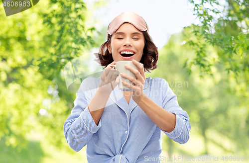 Image of woman in pajama and sleeping mask drinking coffee