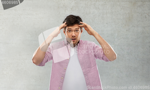 Image of man touching his head over grey concrete wall