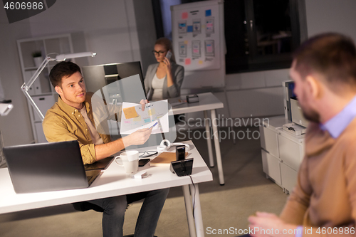 Image of business team with papers working late at office