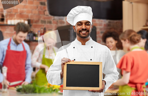 Image of happy indian chef with chalkboard at cooking class