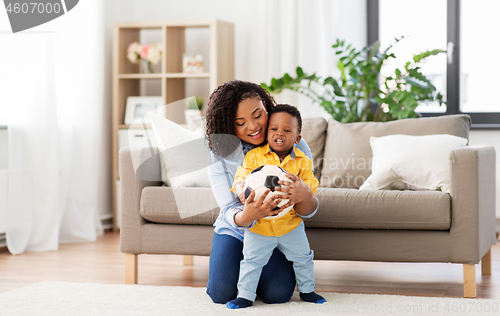 Image of mother and baby playing with soccer ball at home