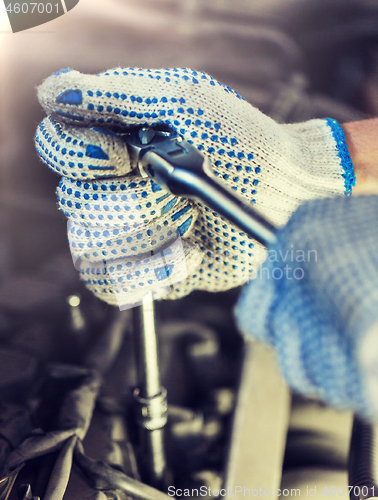 Image of mechanic man with wrench repairing car at workshop