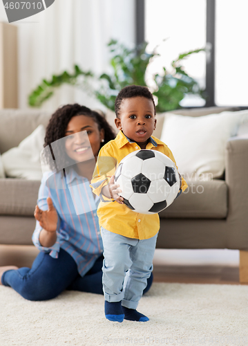 Image of mother and baby playing with soccer ball at home