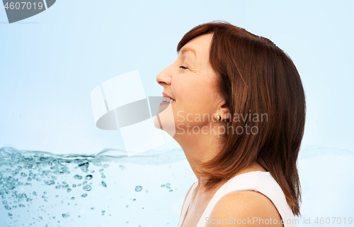 Image of profile of smiling senior woman over blue water