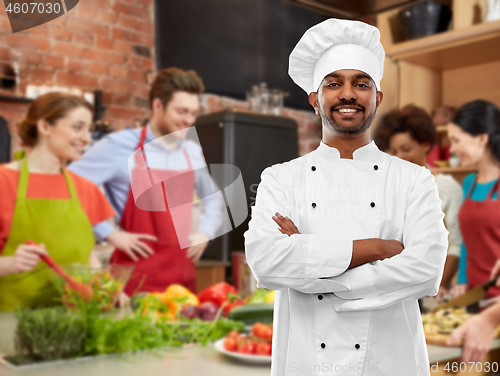 Image of happy male indian chef in toque at cooking class