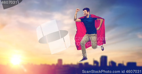 Image of man in superhero cape flying over sunset in city