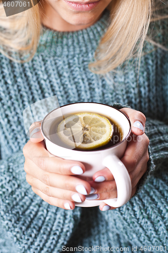 Image of Female hands holding mug of hot tea with lemon in morning. Young