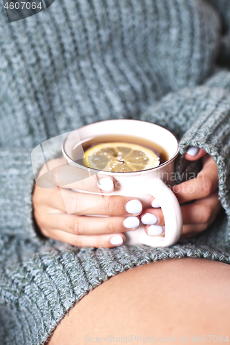 Image of Female hands holding mug of hot tea with lemon in morning. Young