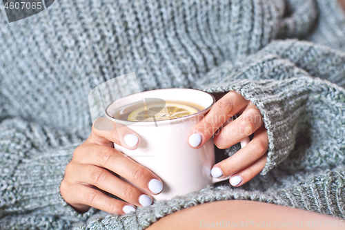 Image of Female hands holding mug of hot tea with lemon in morning. Young