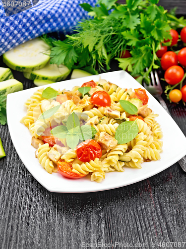 Image of Fusilli with chicken and tomatoes in plate on black board