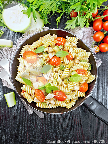 Image of Fusilli with chicken and tomatoes in pan on black board top