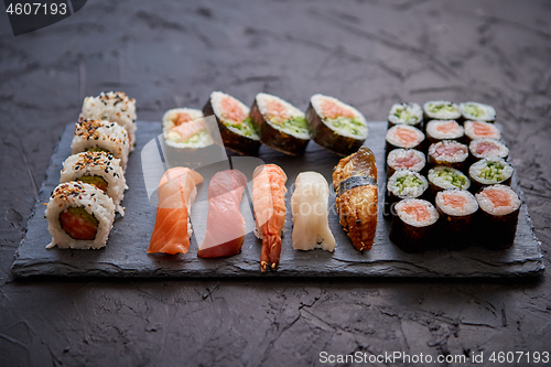 Image of Sushi rolls set with salmon and tuna fish served on black stone board