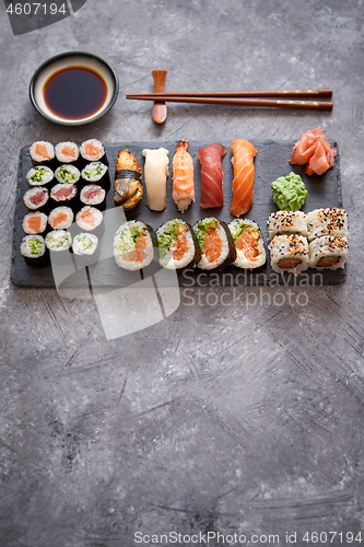 Image of Composition of different kinds of sushi rolls placed on black stone board