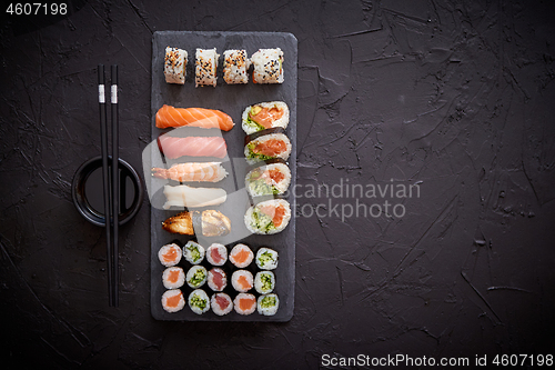 Image of Sushi rolls set with salmon and tuna fish served on black stone board