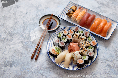 Image of Asian food assortment. Various sushi rolls placed on ceramic plates