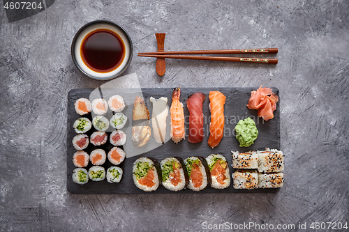 Image of Composition of different kinds of sushi rolls placed on black stone board