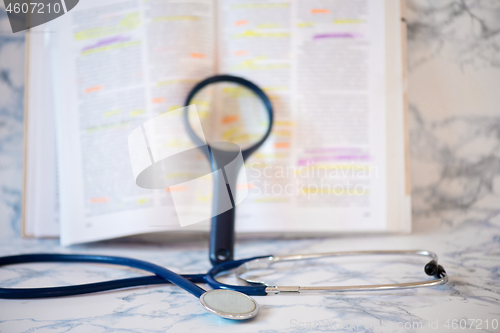 Image of Stethoscope, magnifier and book Tablet in the fingers of hand