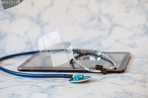 Image of Stethoscope and notebook Tablet in the fingers of hand