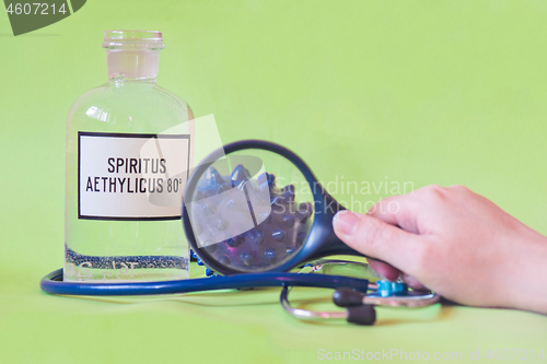 Image of Ethanol in a bottle on the table with of microscope virus close up, stethoscope and loupe. Coronavirus concept Tablet in the fingers of hand