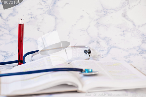 Image of Stethoscope, book and blood analysis Tablet in the fingers of hand