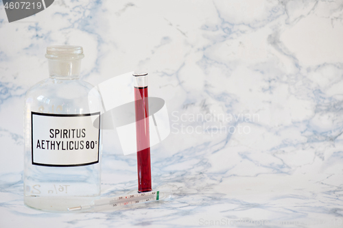 Image of Ethanol in a bottle and blood analysis Tablet in the fingers of hand