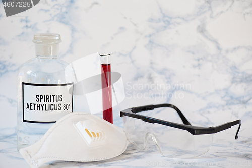 Image of Ethanol in a bottle, protecting mask, blood analysis and glasses Tablet in the fingers of hand