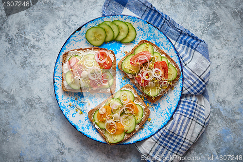 Image of Plate with toasts with cucomber, tomatoes and crumbled feta and radish sprouts