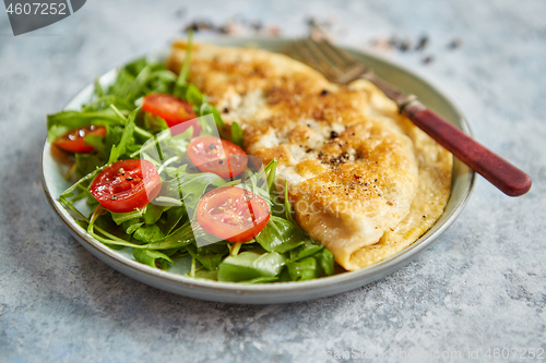 Image of Classic egg omelette served with cherry tomato and arugula salad on side