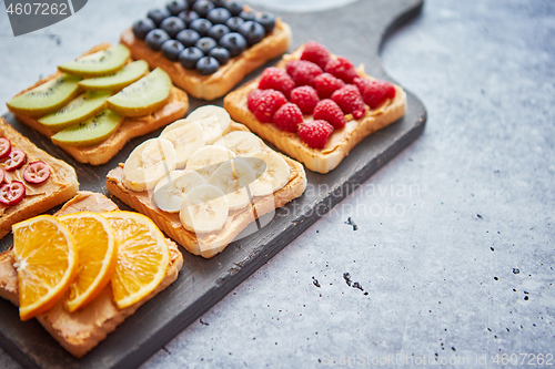 Image of Wholegrain bread slices with peanut butter and various fruits