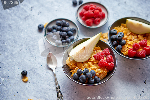 Image of Golden cornflakes with fresh fruits of raspberries, blueberries and pear in ceramic bowl