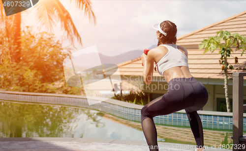 Image of Strong female squatting near swimming pool