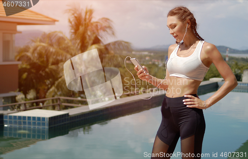 Image of Confident athlete using smartphone on poolside