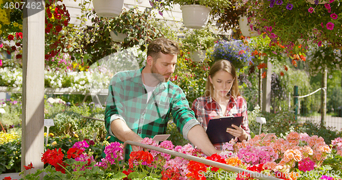 Image of Two Gardeners doing paperwork between plants