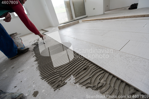 Image of worker installing the ceramic wood effect tiles on the floor