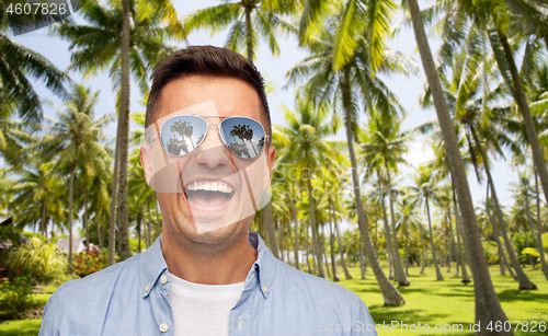 Image of laughing man in sunglasses over tropical beach