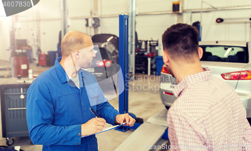 Image of auto mechanic with clipboard and man at car shop