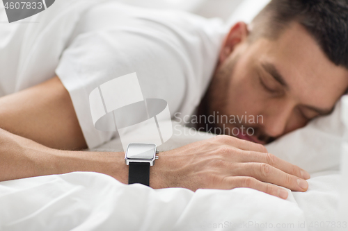 Image of close up of man with smart watch sleeping in bed