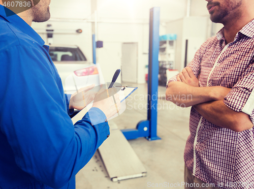 Image of auto mechanic with clipboard and man at car shop