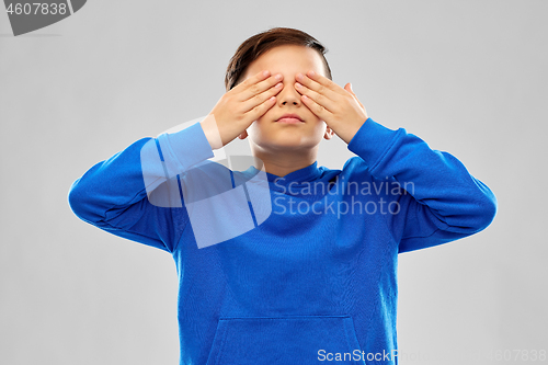Image of boy in blue hoodie closing his eyes by hands