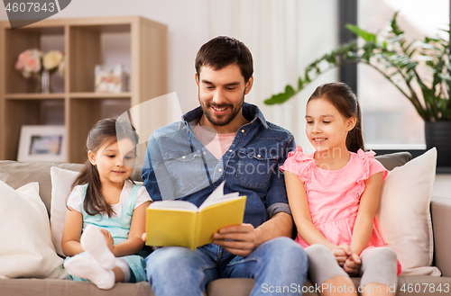 Image of happy father with daughters reading book at home