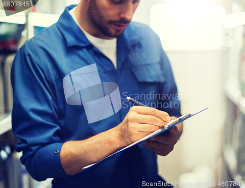 Image of auto mechanic with clipboard at car workshop