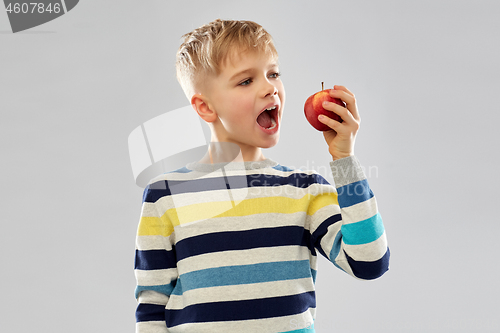 Image of boy in striped pullover eating red apple