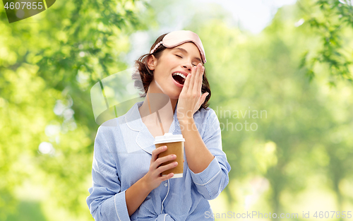 Image of woman in pajama and eye mask with coffee yawning